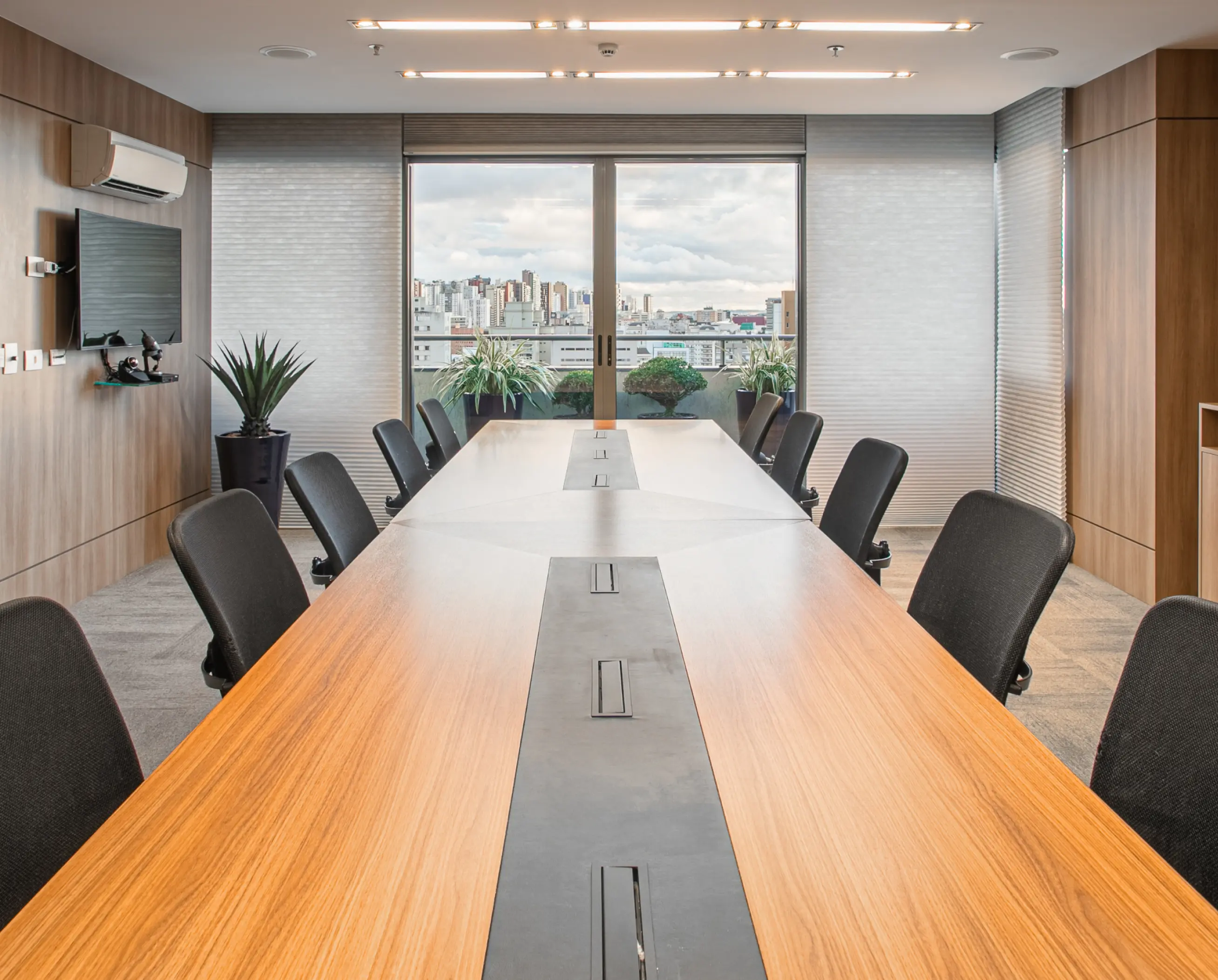 Escritório de advocacia de direito do trabalho e previdenciário, localizado em Curitiba. Sala de reunioes com mesa de madeira, piso de carpet e cadeiras.
